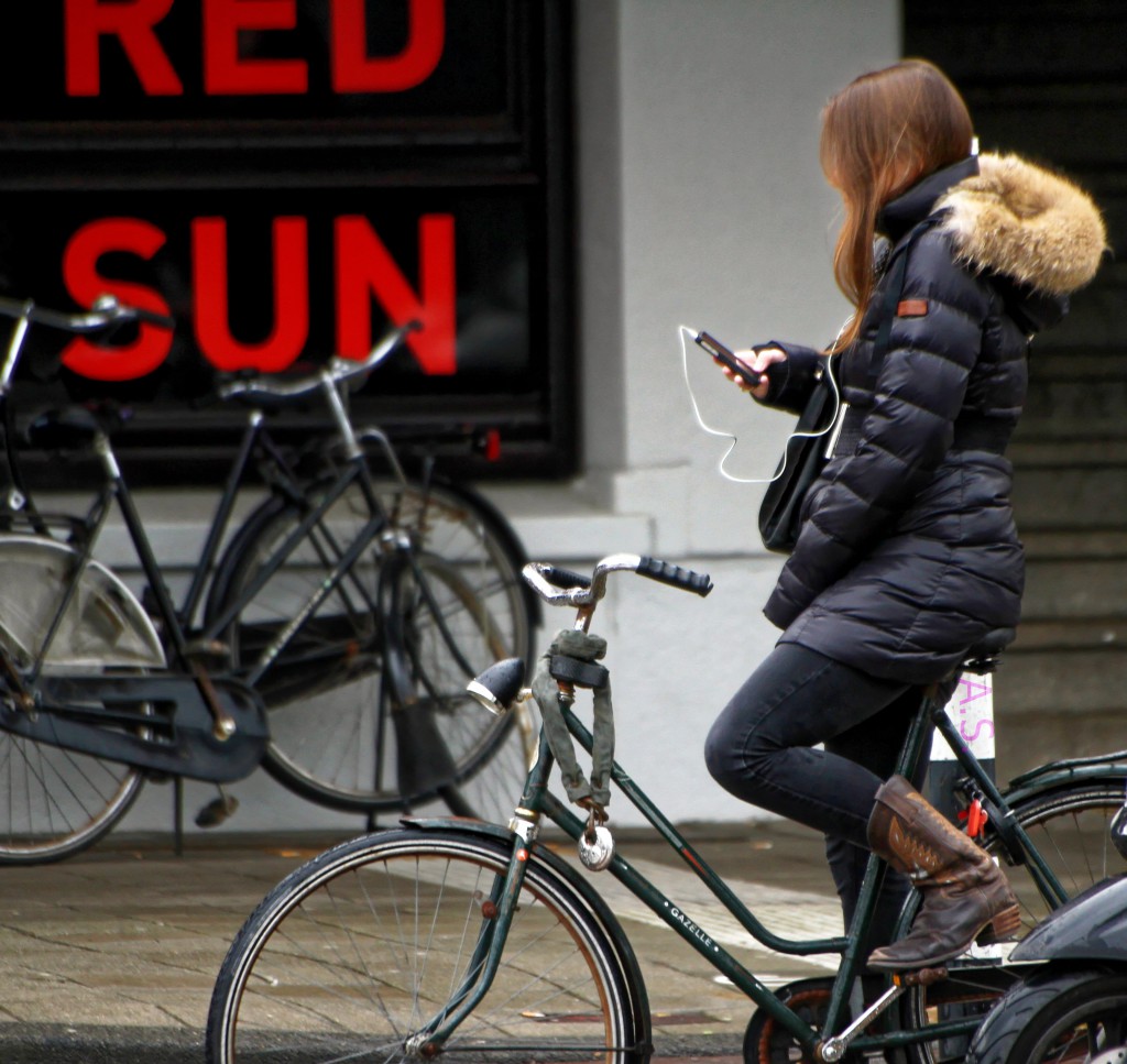 femme sur un vélo qui tien un téléphone portable dans sa main droite